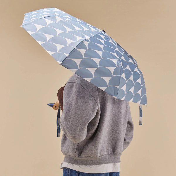 Person Holding an umbrella with blue half circle pattern with duck head handle against a matching background
