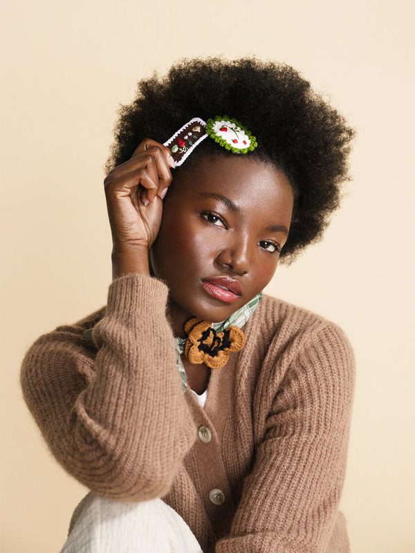 Woman holding a decorative Hansel from basel crocheted hair clips against a beige background