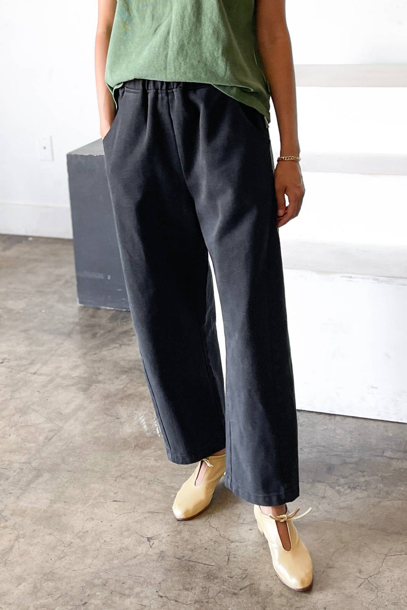 Person wearing dark wide-leg pants and a green top in an indoor setting.