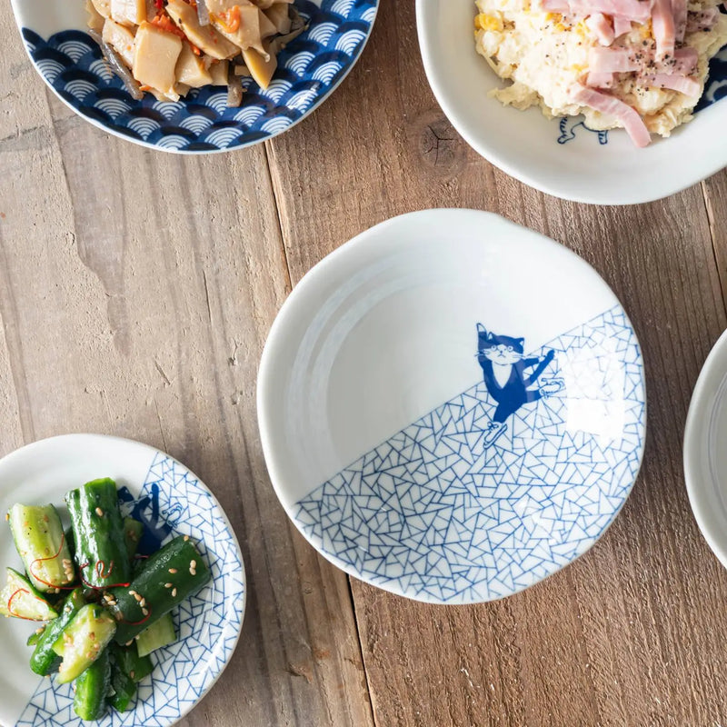 White bowls with blue patterns and a cat ice skating on a wooden surface