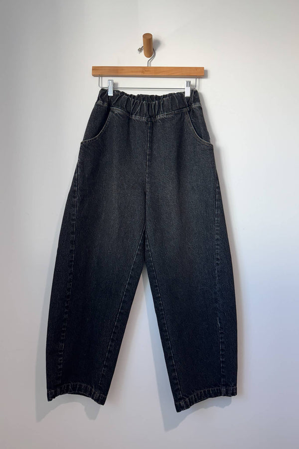 Black jeans hanging on a wooden hanger against a white background