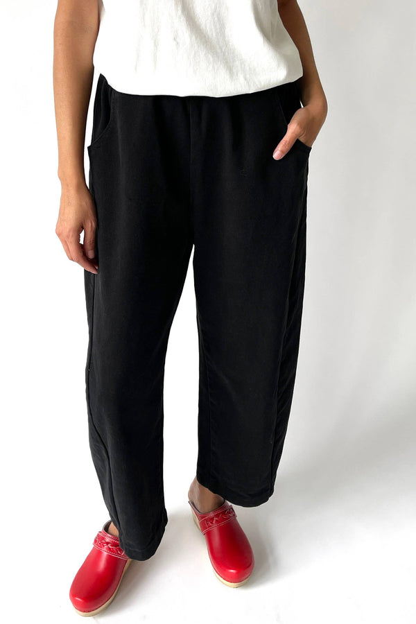 Person wearing black pants and red shoes on a white background