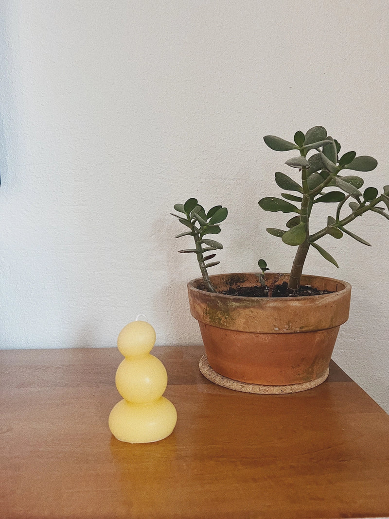 yellow candle wooden surface with a white wall background