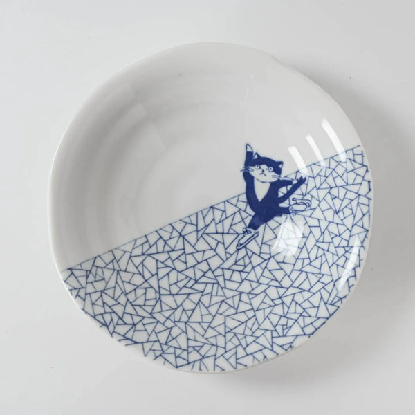 White plate with blue geometric pattern and cat ice skating illustration on a white background