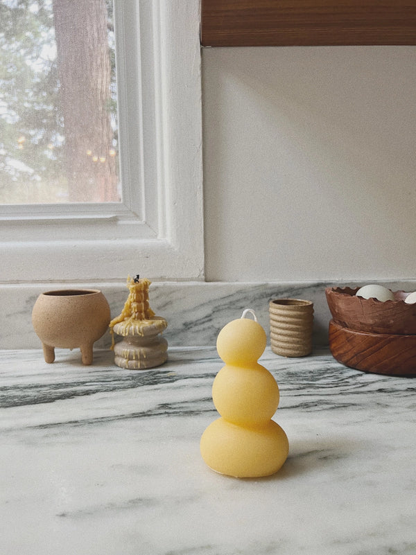 Yellow candle on a marble surface with decorative items in the background