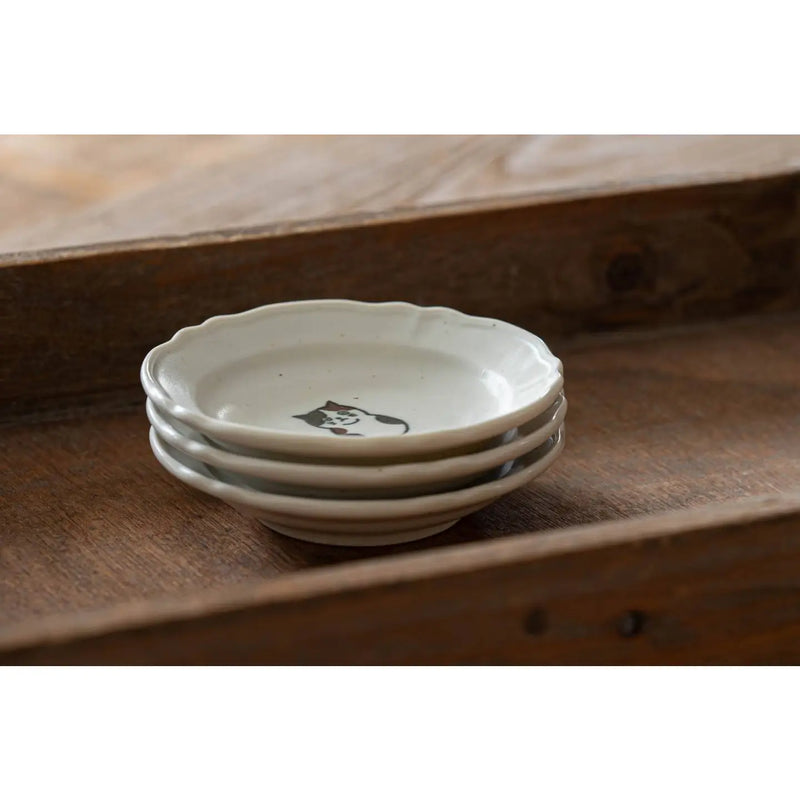 Stack of ceramic bowls with a cat design on a wooden surface
