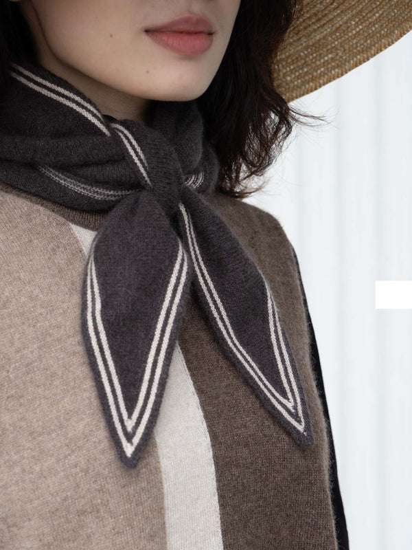 Person wearing a dark brown scarf with white stripes over a brown and beige outfit.