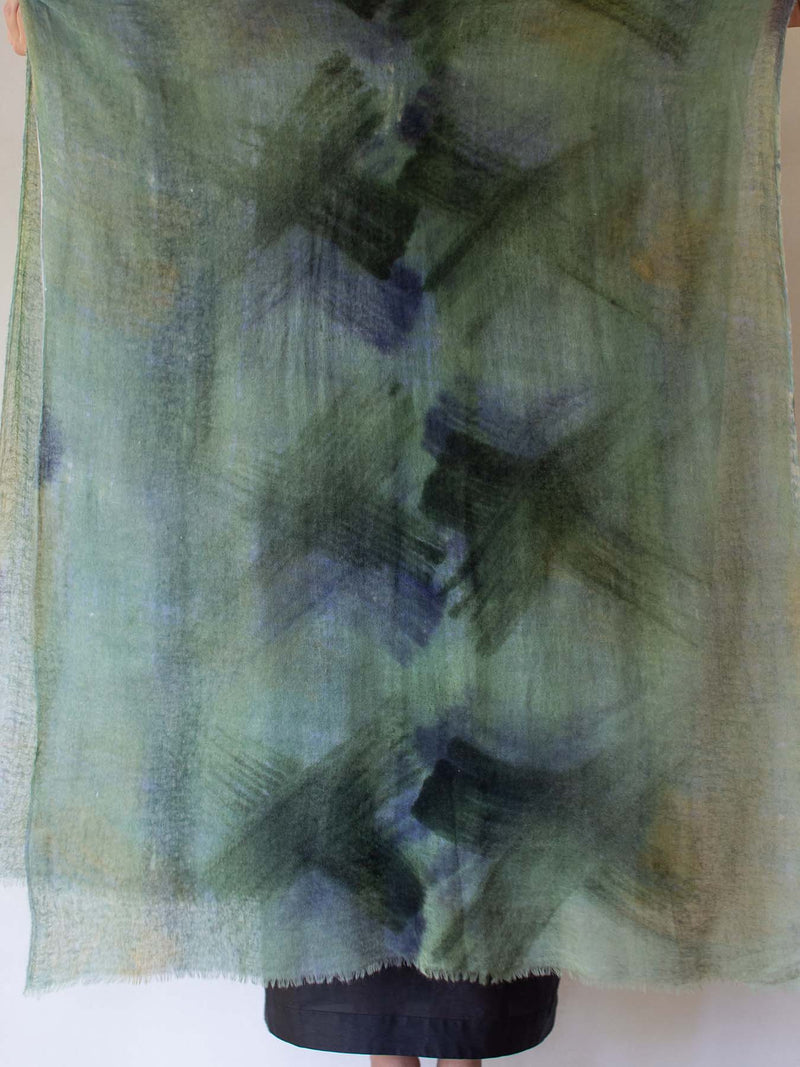 Green and blue patterned scarf held by a person