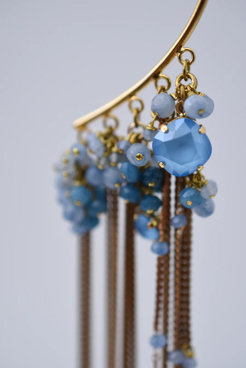Brass ear cuff or ear hook with long  brass chain fringe and blue beads on a white background