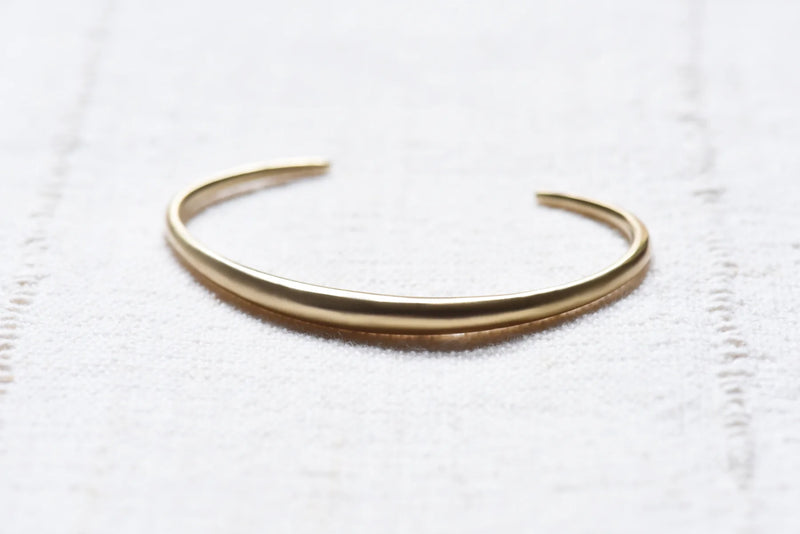 brass bracelet on a white textured surface