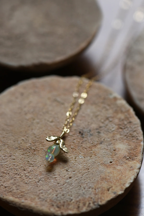 Brass necklace with an opal pendant on a stone surface