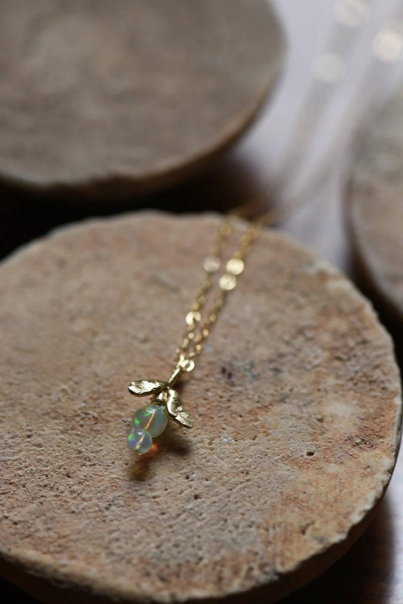Brass necklace with an opal pendant on a stone surface