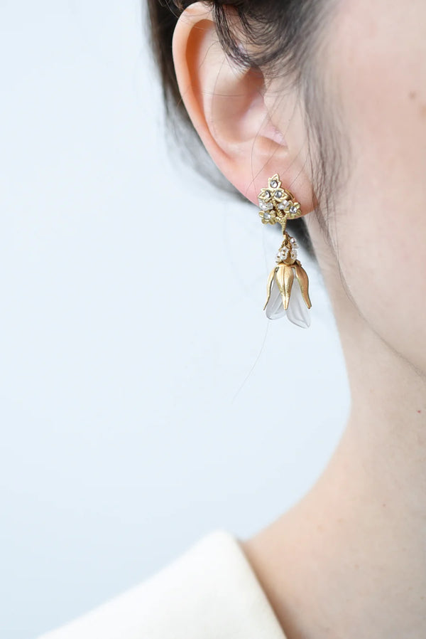 Close-up of a person wearing a floral earring with a light background