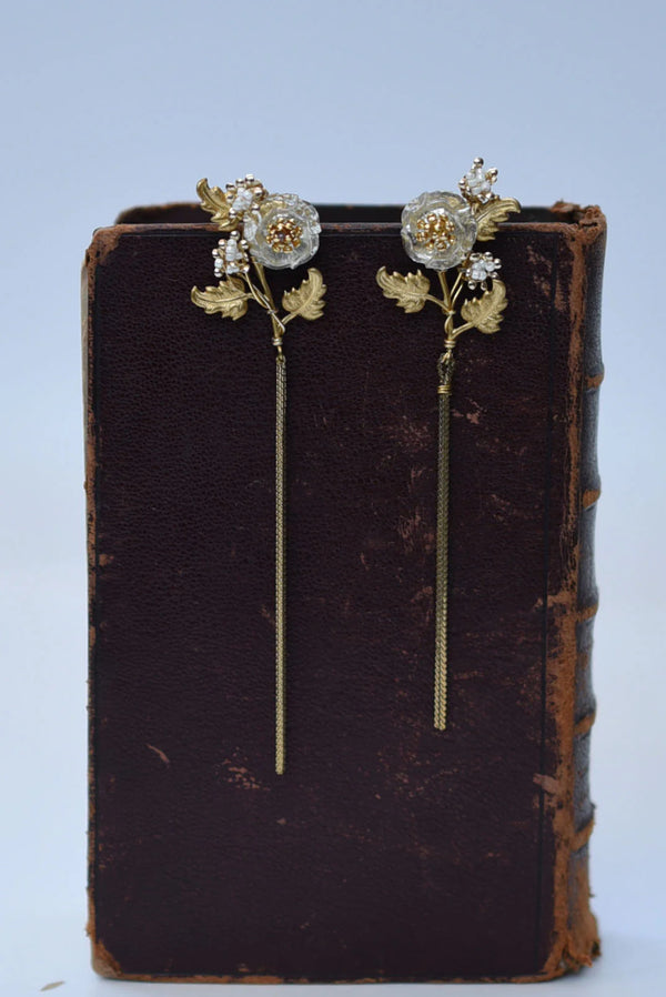 Floral earrings on an old book with a light blue background