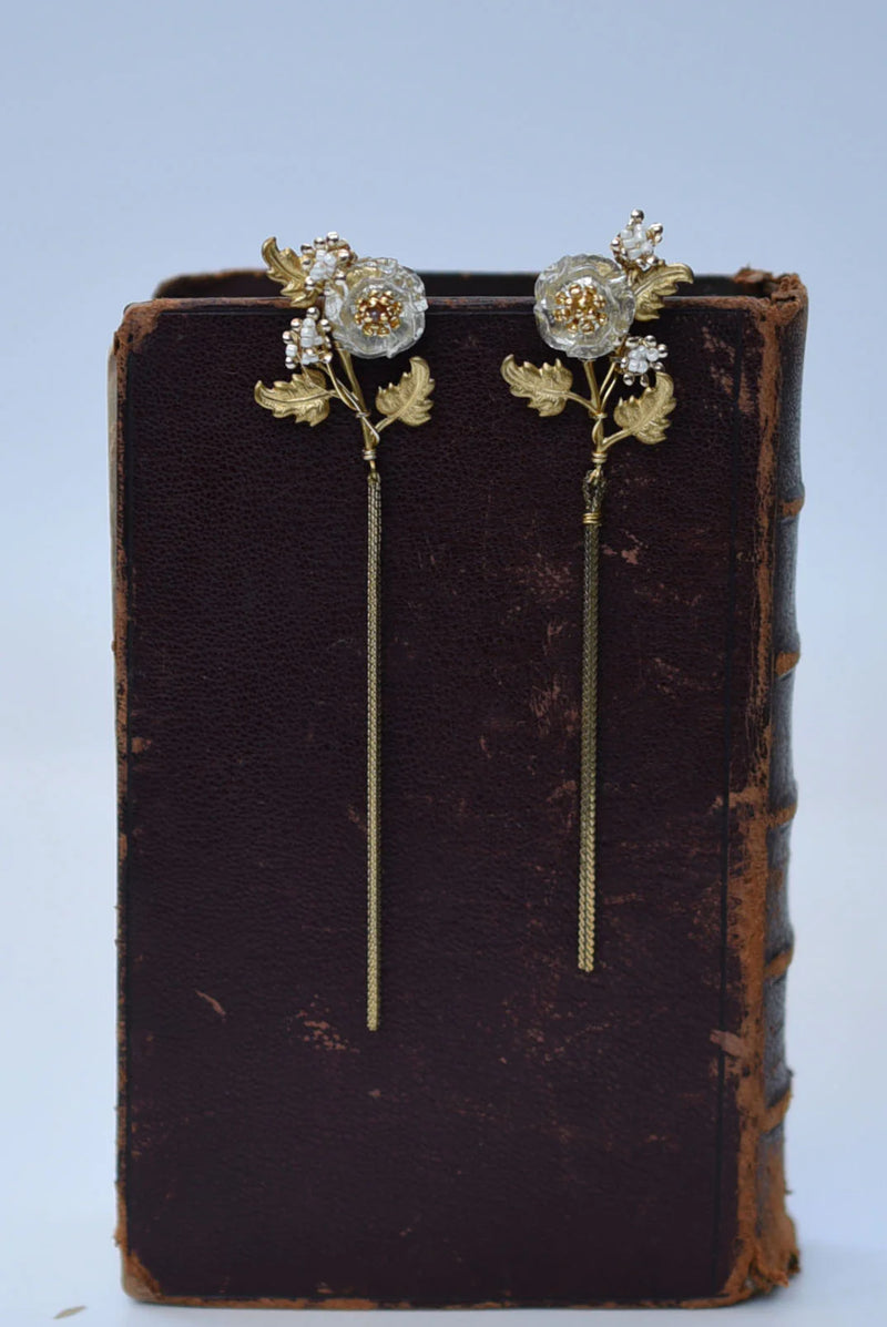 Floral earrings on an old book with a light blue background