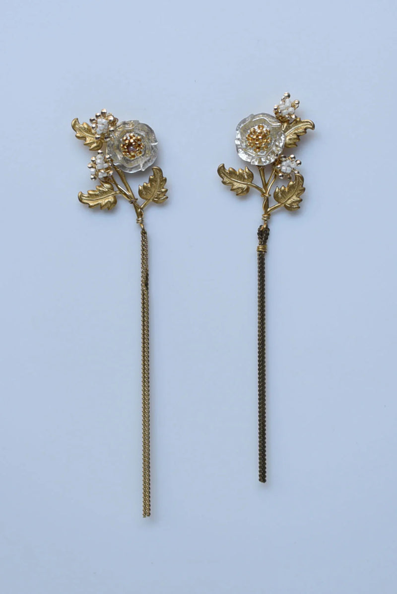 Pair of floral earrings with gold and bronze details on a light blue background
