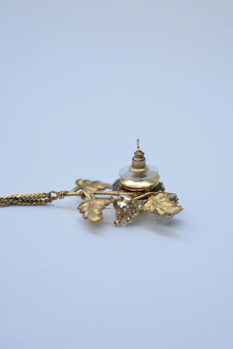 Pair of floral earrings with gold and bronze details on a light blue background