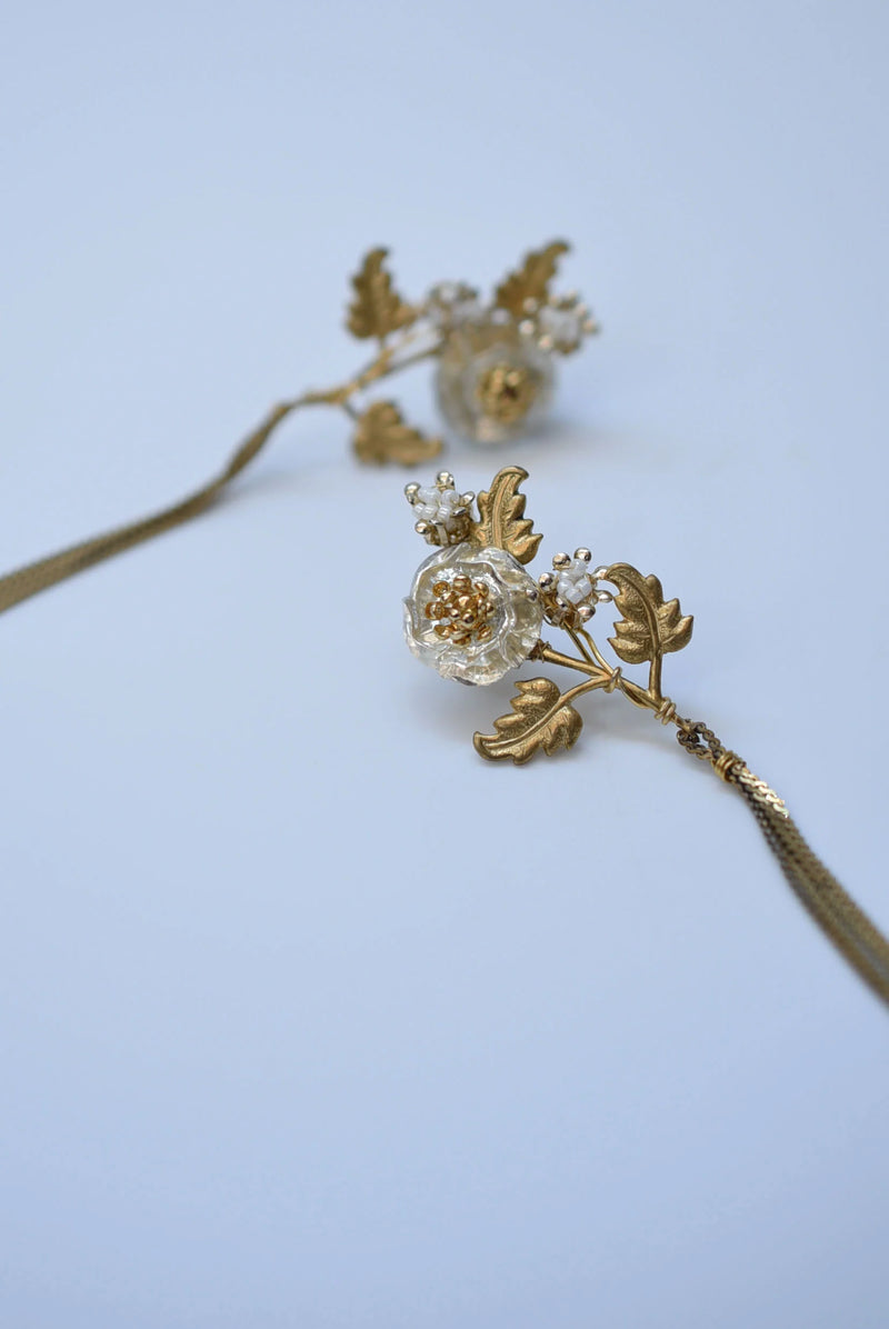 Gold floral hairpin with clear gemstone on a light blue background