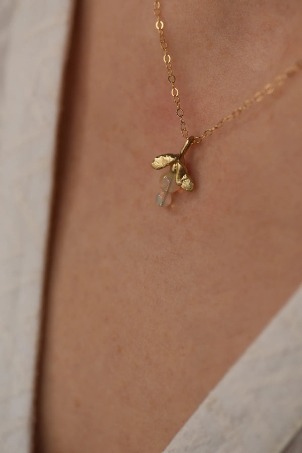 Brass necklace with an opal pendant on a person's neck