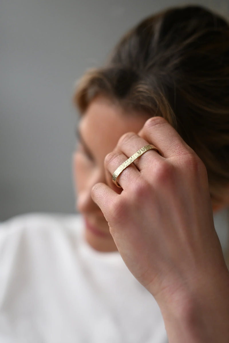 Close-up of a hand wearing a brass ring with a blurred background