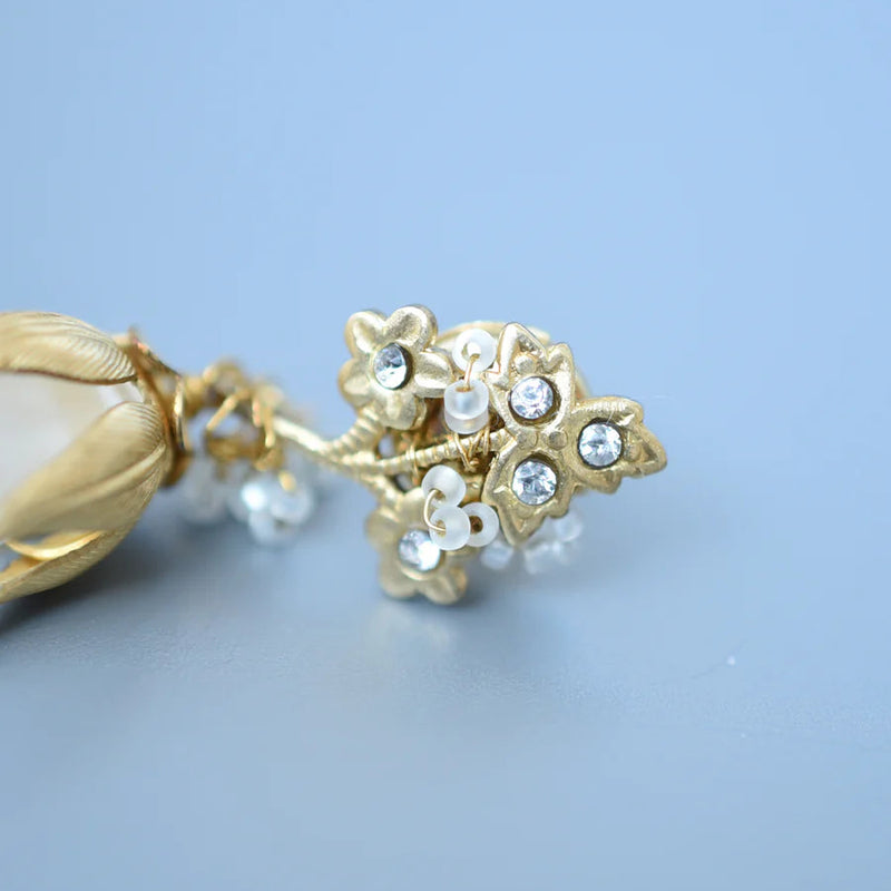 Gold earring with pearls and crystals on a light blue background