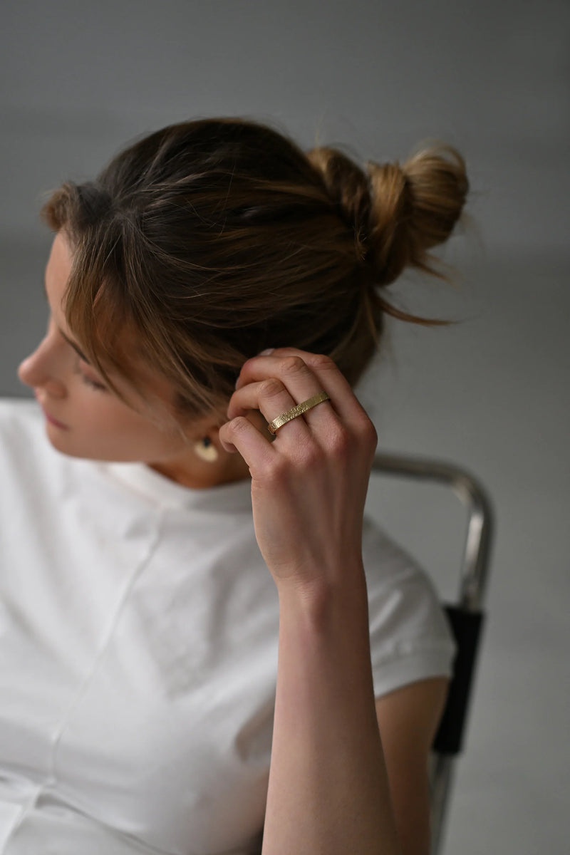 Close-up of a hand wearing a brass ring with a blurred background