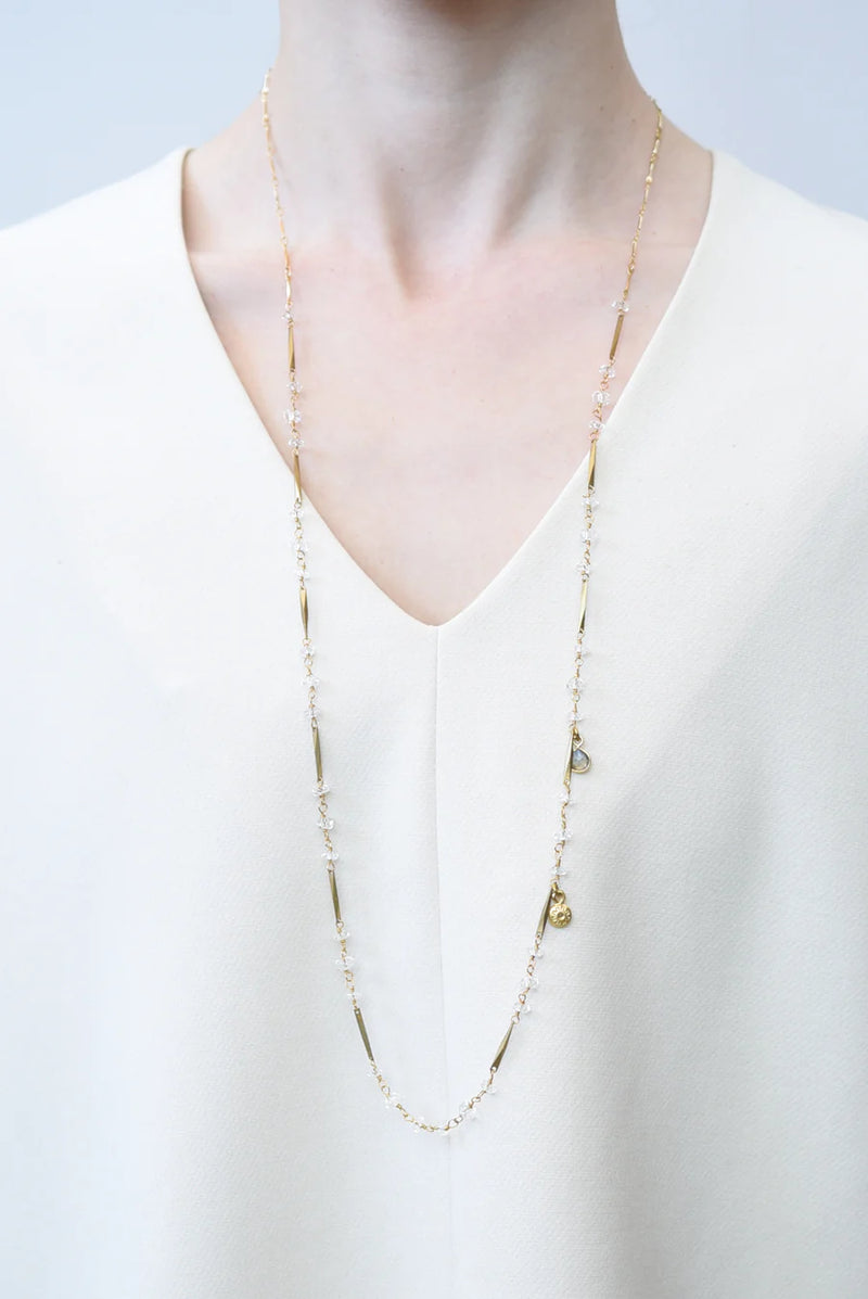 Gold necklace on a white blouse against a light gray background