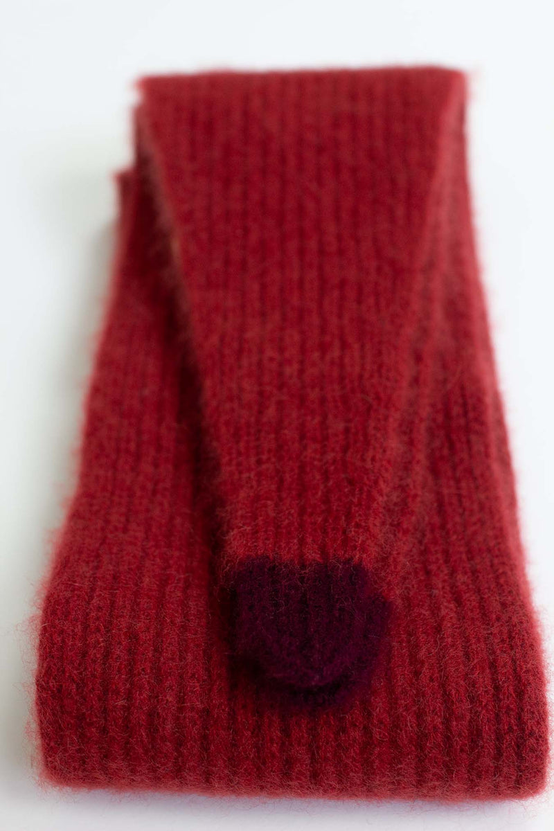 Red knitted scarf with a heart-shaped button on a white background