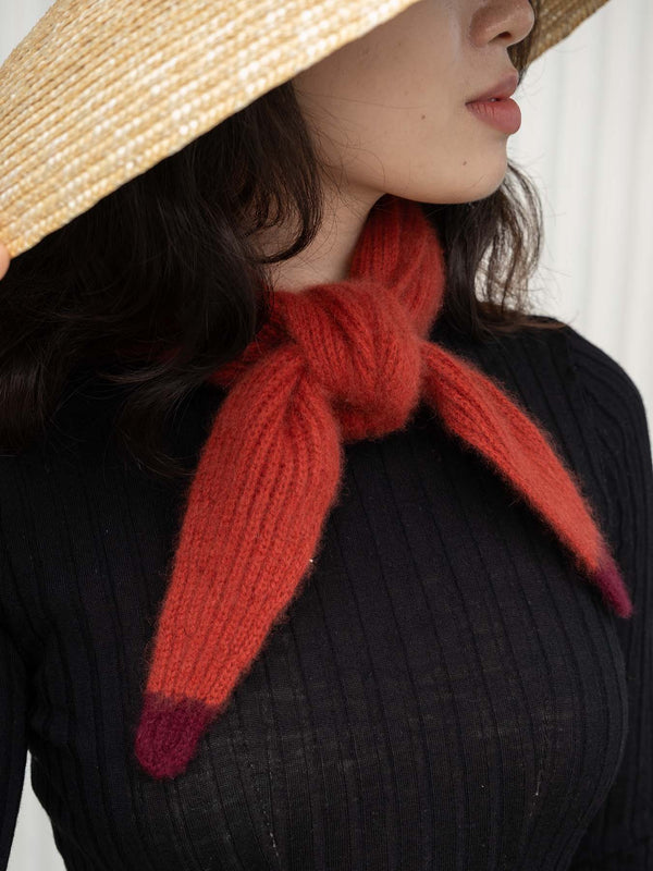 Person wearing a straw hat and red knitted scarf against a white background