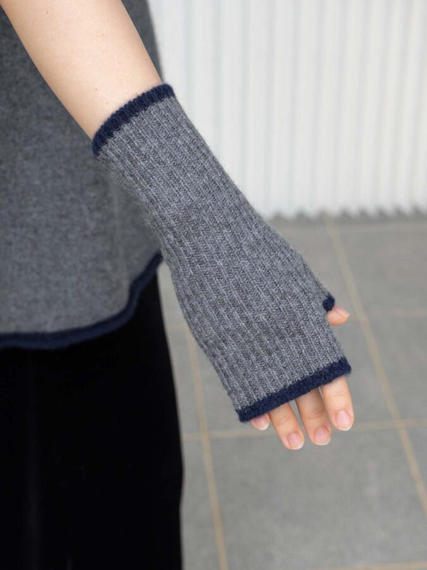 Gray knitted arm warmers with navy trim worn by a person.