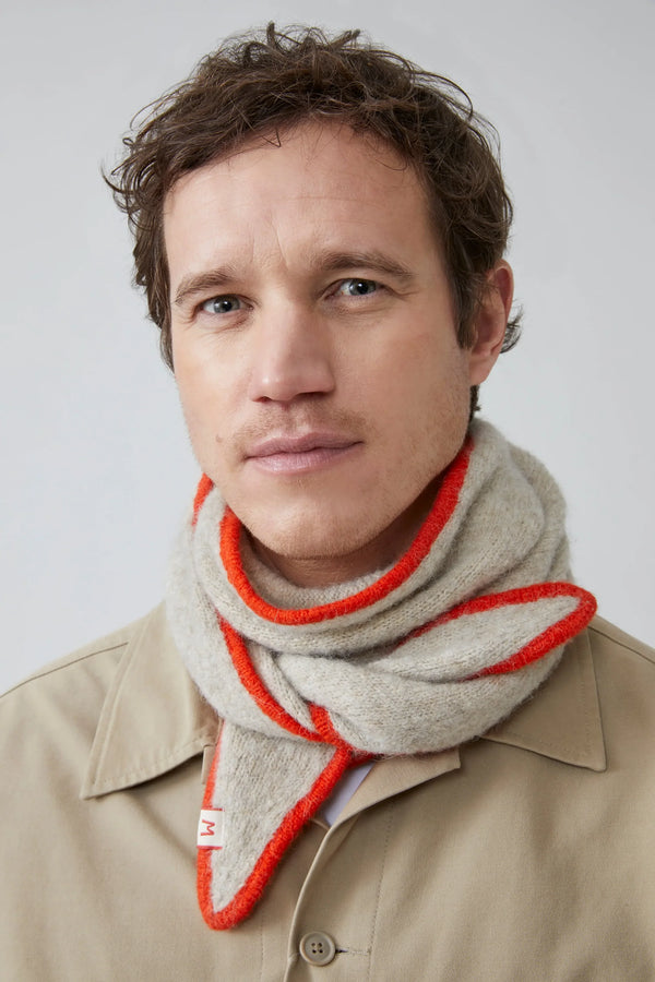 Man wearing a beige scarf with orange trim against a plain background