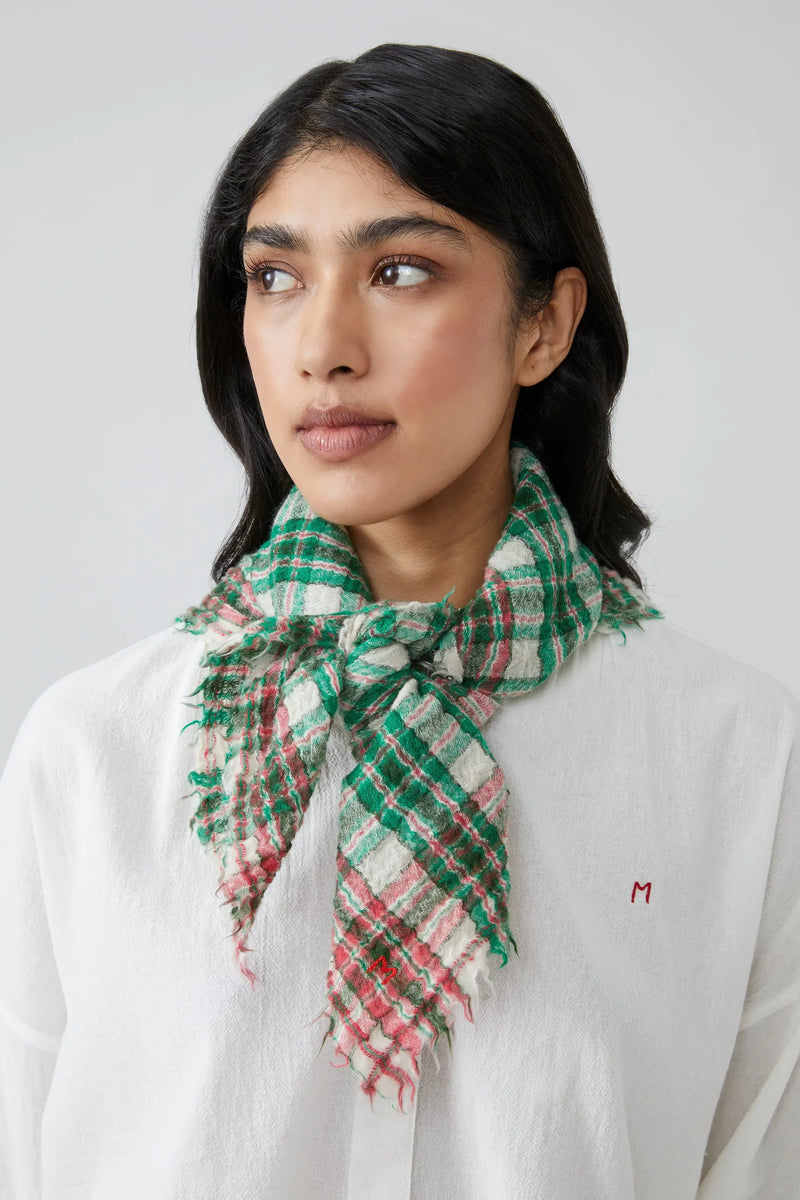 Woman wearing a green and red gingham scarf on a white background