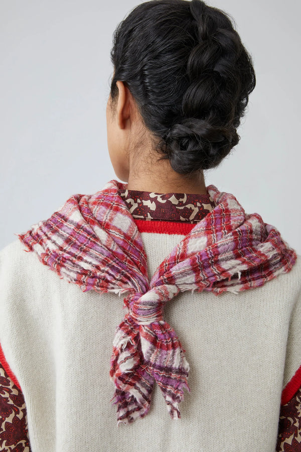 Person wearing a pink, red and white gingham scarf on a plain background