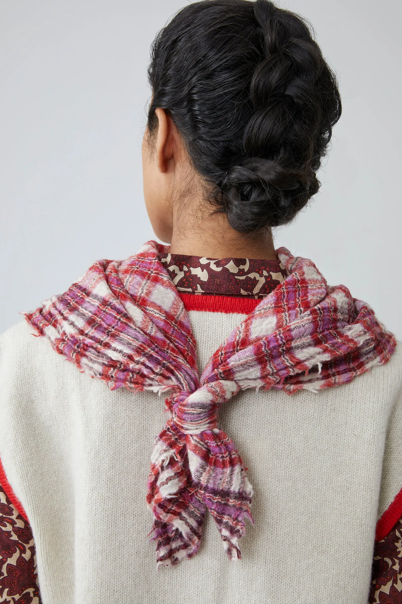 Person wearing a pink, red and white gingham scarf on a plain background