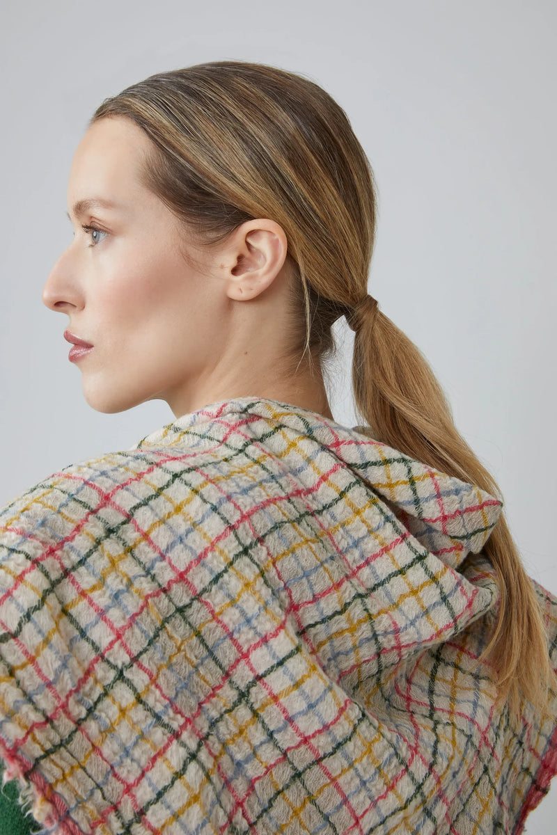 Woman wearing a pink, green, yellow, blue and white gingham scarf against a plain background.