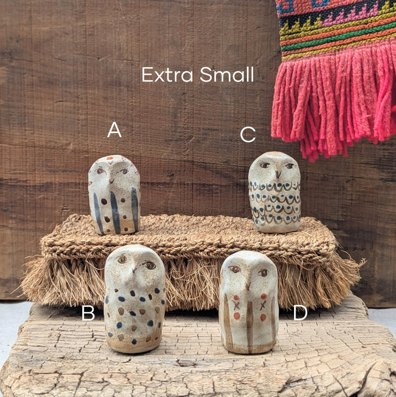 Four exra small owl figurines labeled A, B, C, and D on a wooden surface with a textured background.
