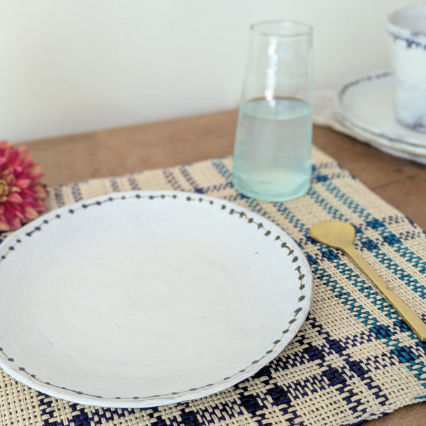 Table setting with a white plate, glass of water, and decorative elements on a woven blue and off white placemat.

Guanabana placemats set kitchen dining handmade woven Colombia gift shop Boston boutique gift sowa