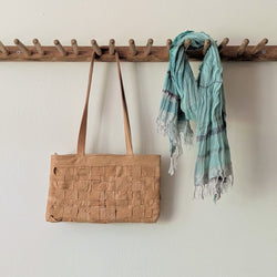 Brown woven bag and green scarf hanging on a wooden rack against a white wall.

Stitch and Tickle Woven Horizonal Shoulder Baguette Tote Bag one of a kind unique leather shop boston New England handmade sowa gift store 