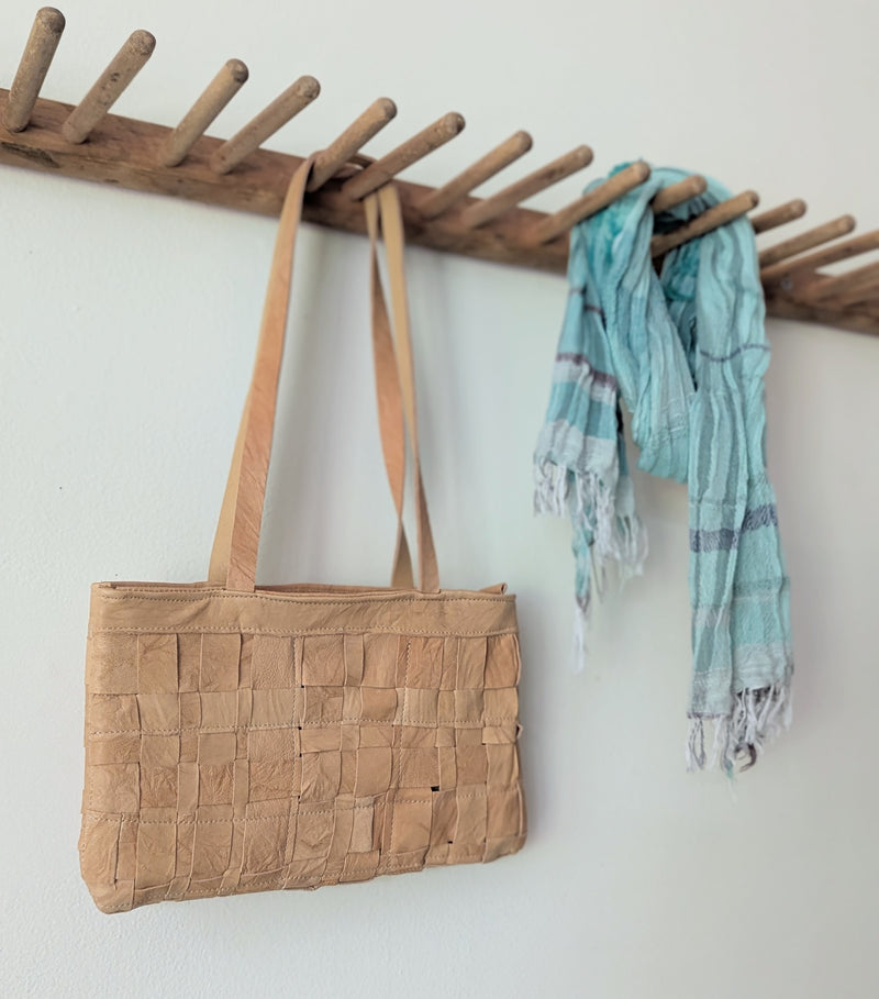 Brown woven bag and light blue scarf hanging on a wooden coat rack against a white wall.

Stitch and Tickle Woven Horizonal Shoulder Baguette Tote Bag one of a kind unique leather shop boston New England handmade sowa gift store 