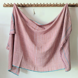 Fabric draped over a wooden rod against a white wall. Auntie Oti Indian cotton lungi woven Khadi wrap throw sarong beach blanket towel tablecloth shop Boston sowa boutique gift store handmade 