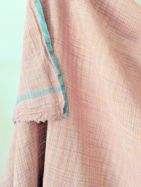 Close-up of a checkered fabric with a light green border on a light green background. Auntie Oti Indian cotton lungi woven Khadi wrap throw sarong beach blanket towel tablecloth shop Boston sowa boutique gift store handmade 