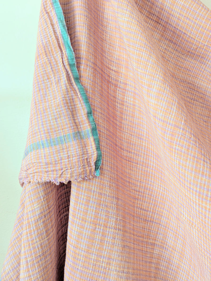 Close-up of a checkered fabric with a light green border on a light green background. Auntie Oti Indian cotton lungi woven Khadi wrap throw sarong beach blanket towel tablecloth shop Boston sowa boutique gift store handmade 
