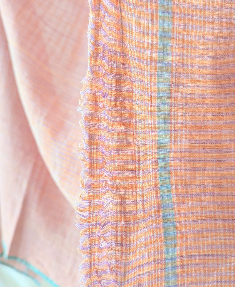 Close-up of a textured fabric with orange and blue patterns. Auntie Oti Indian cotton lungi woven Khadi wrap throw sarong beach blanket towel tablecloth shop Boston sowa boutique gift store handmade 