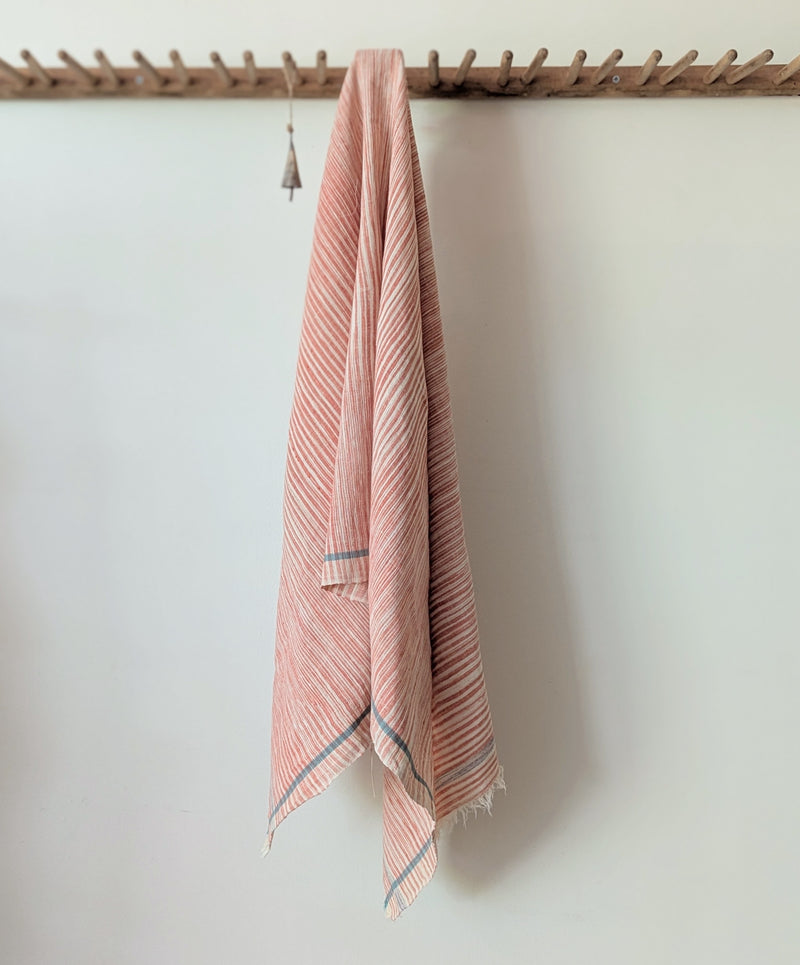 Towel with stripes hanging on a wooden rack against a white wall. Auntie Oti hand woven space dye khadi cotton kitchen hand towel tablecloth beach blanket sowa shop Boston boutique handmade