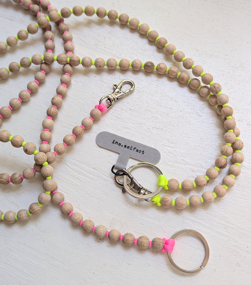 Wooden beaded keychain with neon accents on a white surface. Ina Seifart Handikette Phone Necklace handmade wood beads gift shop sowa boston fashion accessories independent boutique lanyard keychain