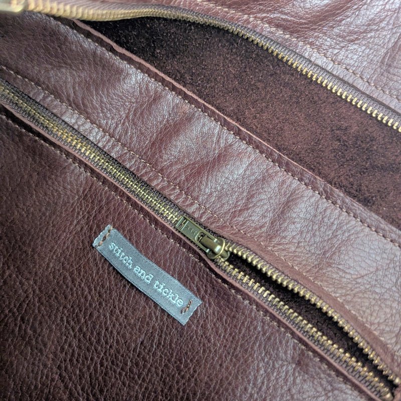 Close up of the inside of a dark leather bag with gold zippered pocket and 'stitch and tickle' label.

Stitch and Tickle everyday carryall leather tote shoulder laptop crossbody work bag handmade boston gift shop sowa independent boutique