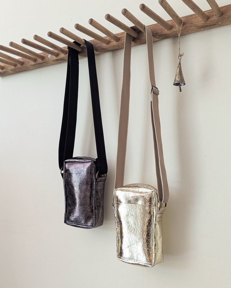 Two metallic handbags hanging on a wooden rack against a white wall.

Stitch and Tickle unisex messenger travel bag adjustable strap shoulder crossbody leatherwork handmade sowa shop Boston gift shop store