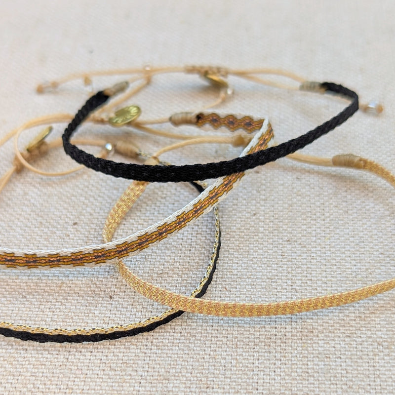 Set of thin woven bracelets in black, gold, and beige on a textured surface

Guanabana woven bracelet handmade jewelry store sowa boston gift shop small business boutique small gifts for her unisex