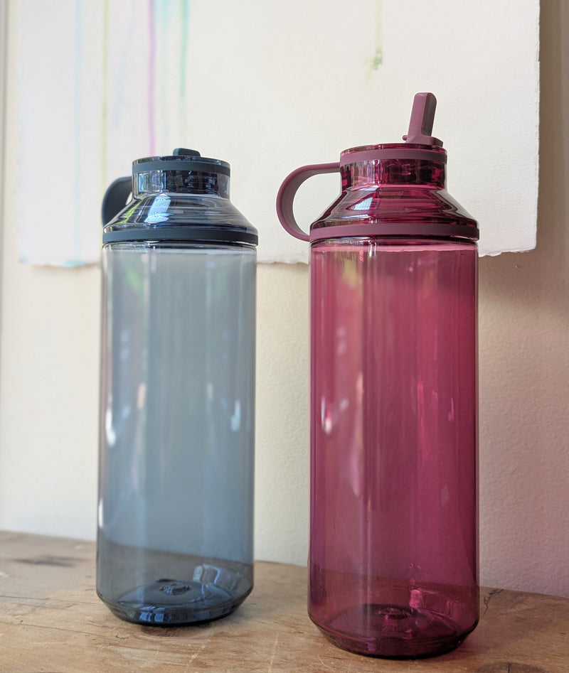 Two reusable plastic water bottles, one blue and one pink, on a wooden surface with a neutral background.

Japanese reusable water bottles plastic travel portable clear transparent BPA free KINTO sowa Boston gift shop boutique store
