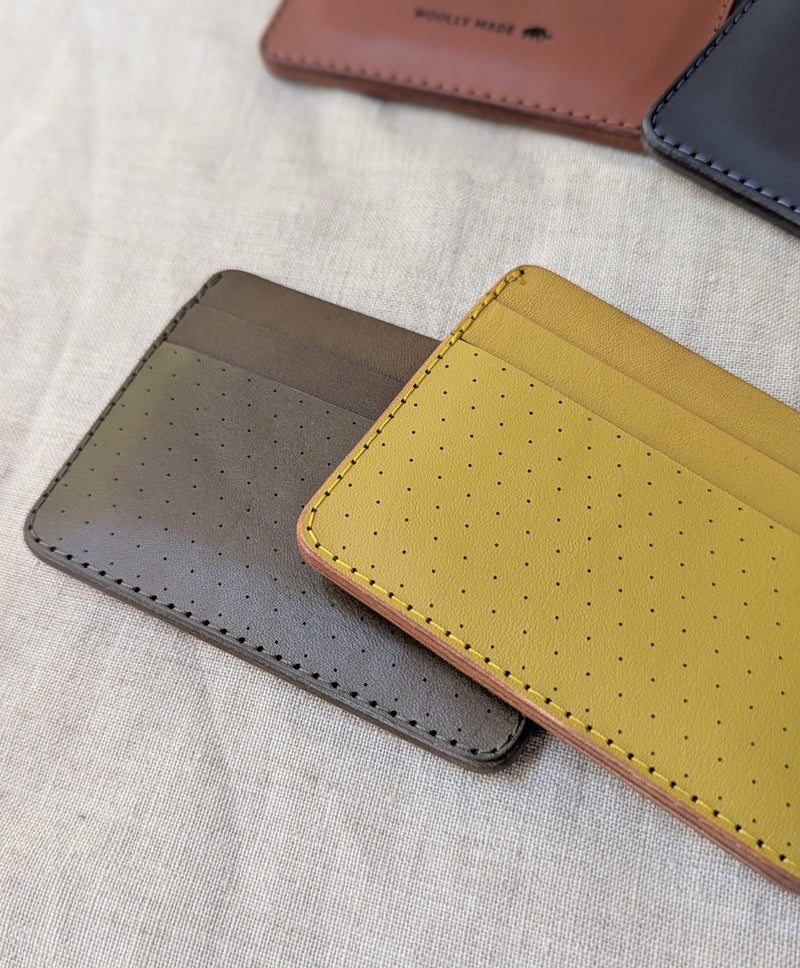 Three leather card holders in brown, gray, and yellow on a textured surface.

Wooly Made cardholder handmade leather small wallet sowa boston small business gift shop boutique gifts for him unisex